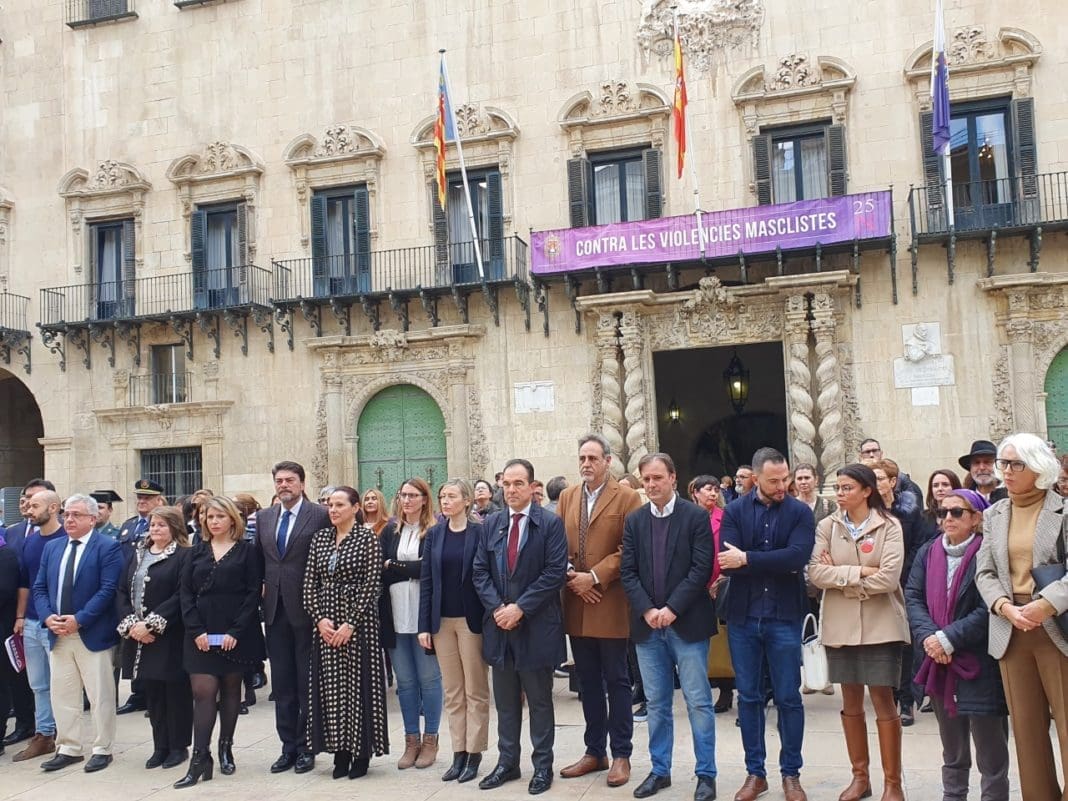 Miembros de la corporación municipal y de la sociedad civil guardando el minuto de silencio con la fachada de Ayuntamiento de Alicante de fondo/ Alex Ferrer