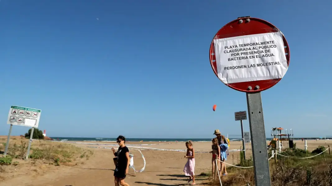 Bañistas junto a una señal de prohibición de bañarse en una playa de Altea