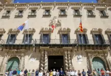 Personas guardan tres minutos de silencio ante la corporación municipal de Alicante.