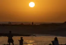 La alerta roja deja hasta 42 grados en Alicante con tormentas, granizo y rachas de 90 km/h Personas caminando en la playa al atardecer, con calor en Alicante