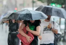 Tres personas caminan bajo la tormenta con lluvia intensa