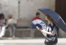 Mujer se abanica y se protege del sol con un paraguas en Valencia
