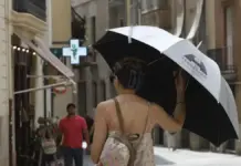 Mujer protegida del sol con un paraguas en la calle, con calor en València