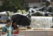 Personas protegiéndose del calor en València en un día de julio