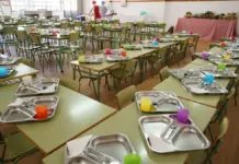 Comedor escolar con bandejas y mesas preparadas para una comida