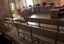 Sala de juicios vacía con asientos y mobiliario en un tribunal
