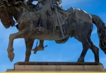 Cartel municipal del 9 d'Octubre que anuncia la Reial Senyera y la espada de Jaume I en València.