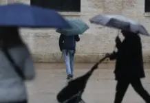 Personas resguardándose de la lluvia bajo paraguas en una escena urbana.