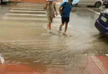 Dos personas cruzan una calle encharcada en Alicante por las lluvias