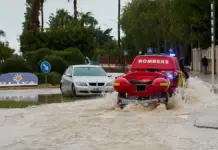 Un vehículo de los Bombers valencianos circula por una avenida inundada en Oliva, Valencia.