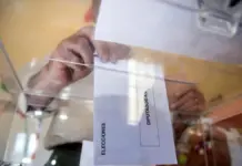 Persona depositando el voto en una urna en un colegio electoral